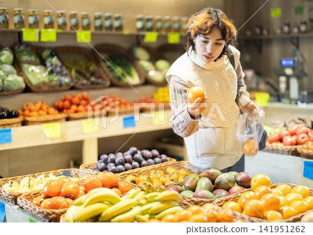 Young woman choosing orange in grocery store Young woman choosing orange in grocery store 141951262