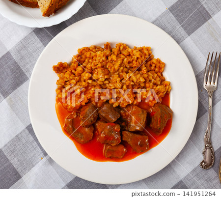 There is portion of hearty food on plate - pearl barley with beef stew in tomato sauce There is portion of hearty food on plate - pearl barley with beef stew in tomato sauce 141951264