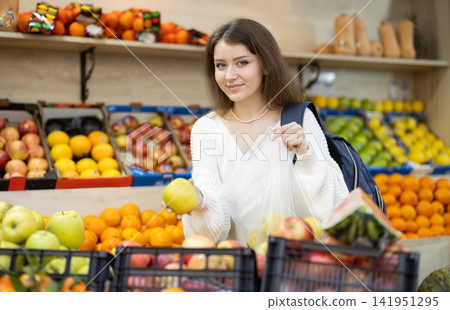Girl choosing ripe apples in grocery supermarket Girl choosing ripe apples in grocery supermarket 141951295