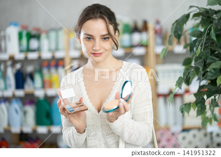 Young woman choosing eyeshadow and powder in store Young woman choosing eyeshadow and powder in store 141951322