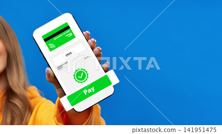 User holds a smartphone displaying an online payment screen against a blue background User holds a smartphone displaying an online payment screen against a blue background 141951475