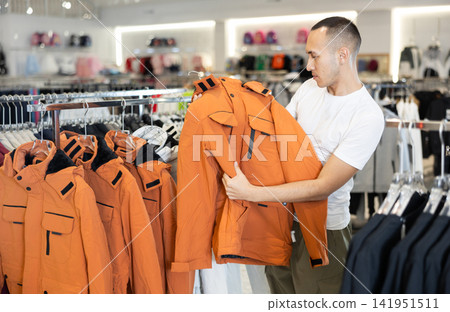 Young man choosing jacket in store 141951511