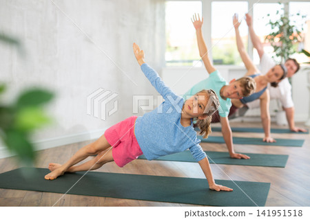 Little girl with family practicing yoga in studio Little girl with family practicing yoga in studio 141951518