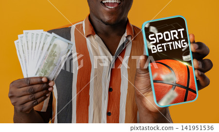 Man happy with money and phone showing sports betting Man happy with money and phone showing sports betting 141951536