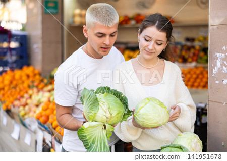 Young couple standing in the market and choosing vegetables Young couple standing in the market and choosing vegetables 141951678