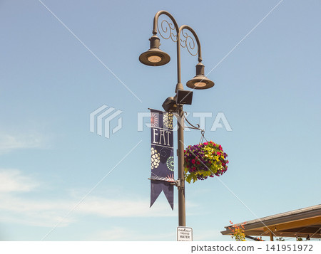 Elegant vintage street light with a hanging flower basket at Point Ruston promenade. - June 13, 2026 Ruston WA, USA Elegant vintage street light with a hanging flower basket at Point Ruston promenade. - June 13, 2026 Ruston WA, USA 141951972