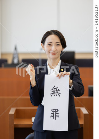 A female lawyer holds up a "not guilty" document in court and makes a triumphant gesture. A female lawyer holds up a "not guilty" document in court and makes a triumphant gesture. 141952137