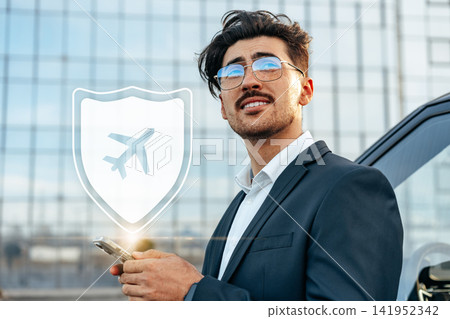 Travel booking process with a man using a phone near an airport with a digital shield icon shown Travel booking process with a man using a phone near an airport with a digital shield icon shown 141952342
