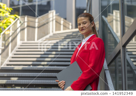 Businesswoman successful woman standing outdoor corporate building exterior. Caucasian confidence professional business woman in red suit. Businesswoman successful woman standing outdoor corporate building exterior. Caucasian confidence professional business woman in red suit. 141952349