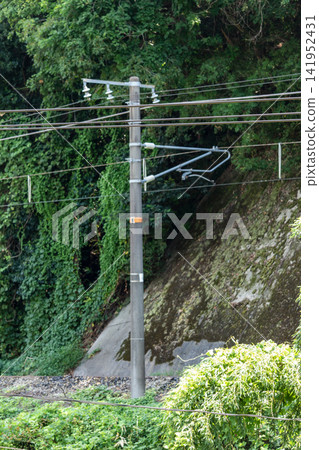 穿過山區的鐵路架空電線桿和電線(垂直構圖,背景是山坡和綠色植物) 穿過山區的鐵路架空電線桿和電線(垂直構圖,背景是山坡和綠色植物) 141952431