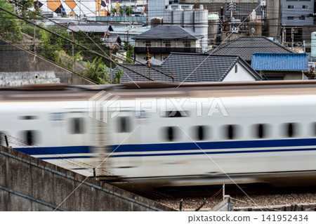 A bullet train speeds past with the cityscape in the background. A bullet train speeds past with the cityscape in the background. 141952434