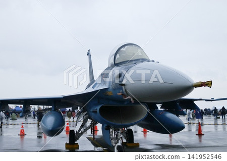 A camouflaged fighter jet stands silently on a rainy runway. A camouflaged fighter jet stands silently on a rainy runway. 141952546