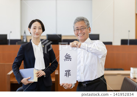 一名委託人和一名女律師在法庭上舉著一份無罪證明文件。 一名委託人和一名女律師在法庭上舉著一份無罪證明文件。 141952834