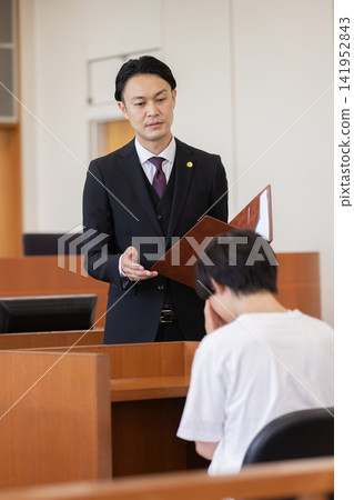 A lawyer speaking to the defendant in court A lawyer speaking to the defendant in court 141952843