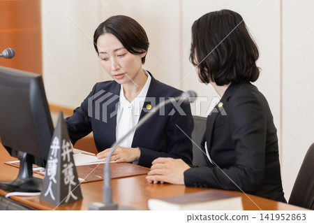 A team of female lawyers holding a meeting in court. A team of female lawyers holding a meeting in court. 141952863