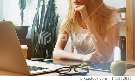 E learning setting with a person focused on work at a desk with a laptop and tablet E learning setting with a person focused on work at a desk with a laptop and tablet 141952985