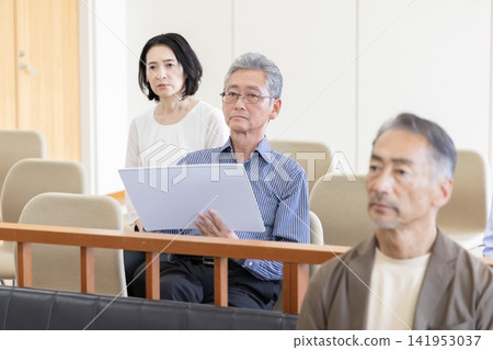 A man watches the trial from the courtroom gallery, drawing satirical cartoons. A man watches the trial from the courtroom gallery, drawing satirical cartoons. 141953037