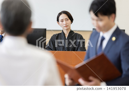 A scene from a trial where a female judge observes testimony in court. A scene from a trial where a female judge observes testimony in court. 141953078