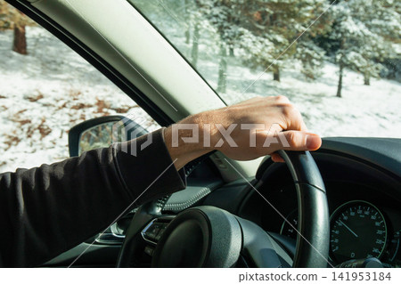 Winter travel. Driver maintains control on snowy road while wearing winter gear Winter travel. Driver maintains control on snowy road while wearing winter gear 141953184