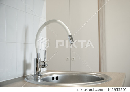 Contemporary kitchen features a clean stainless steel sink and stylish faucet Contemporary kitchen features a clean stainless steel sink and stylish faucet 141953201