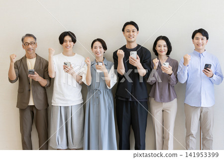 A group of Japanese people of all generations holding smartphones and making victory poses. A group of Japanese people of all generations holding smartphones and making victory poses. 141953399