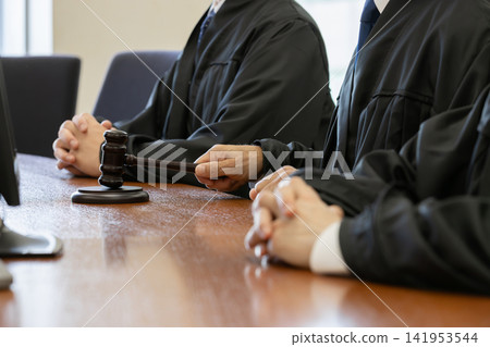 Close-up of a judge's hands striking a wooden mallet in court. Close-up of a judge's hands striking a wooden mallet in court. 141953544