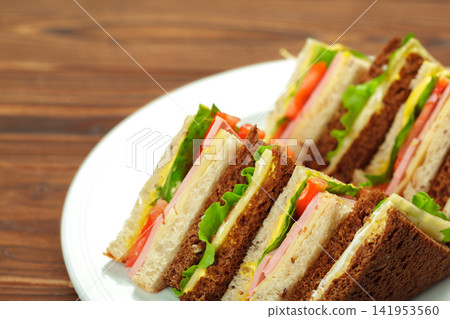 Sliced club sandwiches stacked on a white plate Sliced club sandwiches stacked on a white plate 141953560