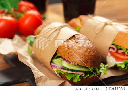 Prepared sandwiches with vegetables and ham in brown paper Prepared sandwiches with vegetables and ham in brown paper 141953634