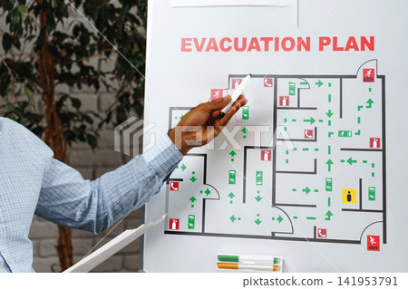 Emergency evacuation plan displayed on a board with marked pathways and exits Emergency evacuation plan displayed on a board with marked pathways and exits 141953791