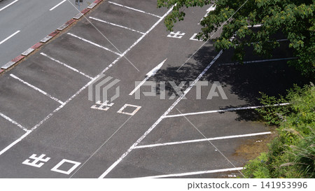 An empty parking lot with exit signs, white lines, and the shadows of trees stretching out before you. An empty parking lot with exit signs, white lines, and the shadows of trees stretching out before you. 141953996