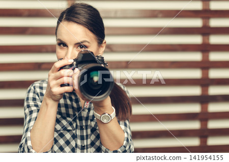 Woman taking a Picture with Digital Camera in Front of Wood Wall Woman taking a Picture with Digital Camera in Front of Wood Wall 141954155
