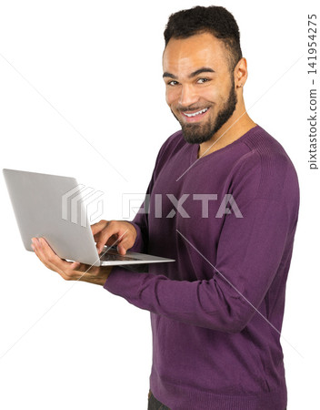Young man uses laptop in bright studio looking at camera Young man uses laptop in bright studio looking at camera 141954275