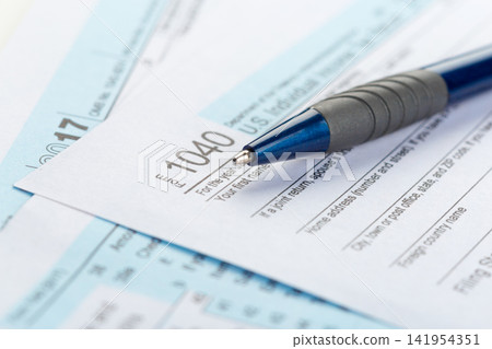 Filling out tax form 1040 in a home office during tax season Filling out tax form 1040 in a home office during tax season 141954351