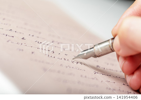 Hand holding a fountain pen while writing on a sheet of paper Hand holding a fountain pen while writing on a sheet of paper 141954406