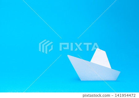 Paper boat floats on a solid light blue background Paper boat floats on a solid light blue background 141954472