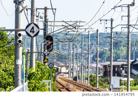 藍天下延伸的鐵軌和鐵路設備(號誌燈、架空電線桿、標示牌)。 藍天下延伸的鐵軌和鐵路設備(號誌燈、架空電線桿、標示牌)。 141954795