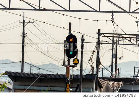 Railway departure signals and overhead lines indicating a reduction in speed (yellow and blue lights on). Railway departure signals and overhead lines indicating a reduction in speed (yellow and blue lights on). 141954798