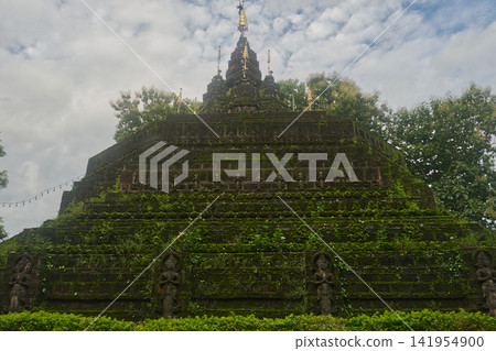 Faith shrouded in green lush grass and moss of Buddhist pagoda at Wat Tham Pla in Northern Thailand Faith shrouded in green lush grass and moss of Buddhist pagoda at Wat Tham Pla in Northern Thailand 141954900