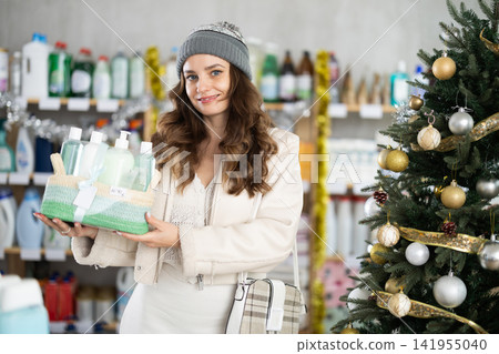 In household chemicals store, woman examines composition of shower cosmetic kit, X Mas gift set In household chemicals store, woman examines composition of shower cosmetic kit, X Mas gift set 141955040