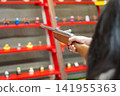 A girl's hands playing in a shooting gallery with a retro Showa-era atmosphere. 141955363