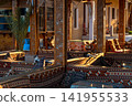 Cafe interior designed in Arabic style, featuring colorful carpets and wooden decor. The space is warm and inviting, with intricate patterns and cozy seating areas. 141955533