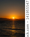 Sunrise over the Red Sea in Dahab, Egypt. The sun rises above the horizon, illuminating the water. Mountains of Saudi Arabia are visible in the background. 141955547