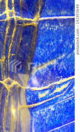 Closeup of polished blue lapis lazuli stone with gold pyrite veining, layered mineral bands, granular texture, and reflective surface under bright directional light Closeup of polished blue lapis lazuli stone with gold pyrite veining, layered mineral bands, granular texture, and reflective surface under bright directional light 141955649