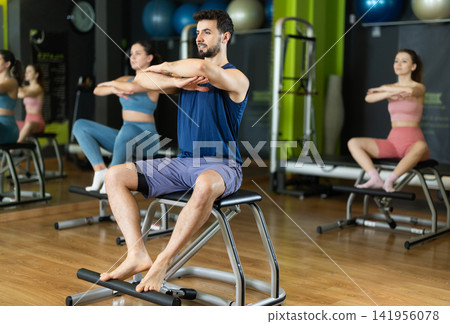 Young man doing leg presses on pilates chair Young man doing leg presses on pilates chair 141956078