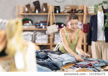 Search and selection of new jeans in a clothing store for young girl Search and selection of new jeans in a clothing store for young girl 141956175