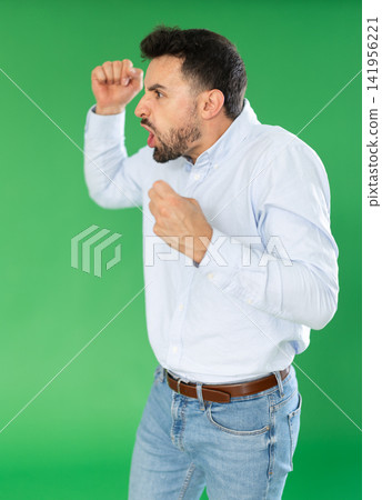 Adult man angry and yelling in front of green screen Adult man angry and yelling in front of green screen 141956221