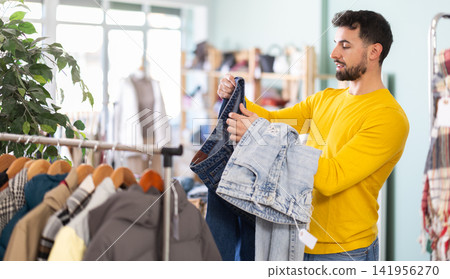 Young man choosing jeans in clothing store Young man choosing jeans in clothing store 141956270