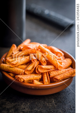 Spicy Rolled Corn Snacks in Bowl With Seasoning . Crunchy Orange Party Snack Closeup Spicy Rolled Corn Snacks in Bowl With Seasoning . Crunchy Orange Party Snack Closeup 141956483