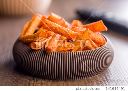 Spicy Corn Snack Chips in Bowl on Wooden Table With TV Remote for Movie Night Spicy Corn Snack Chips in Bowl on Wooden Table With TV Remote for Movie Night 141956491