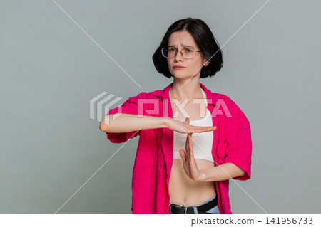 Young woman showing timeout gesture with hands seriously asking for pause break stop communication Young woman showing timeout gesture with hands seriously asking for pause break stop communication 141956733
